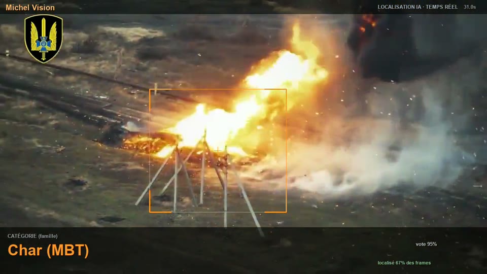 Explosion et flammes au milieu de hérissons antichars, vues du ciel, zone encadrée en orange.